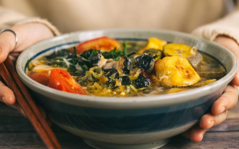 alt text: Thưởng thức bún ốc sườn cùng rau sống và mắm tôm